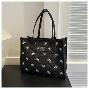 Detail of black tote bag with white rose embroidery and Fashion Instinct label on desktop