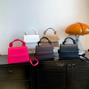 Sacs bandoulière carrés minimalistes à poignées nouées en cinq couleurs sur un meuble