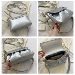 Détails d'un sac bandoulière argenté plissé avec fermoir magnétique doré et bandoulière réglable