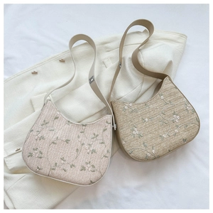 Close-up of woven straw shoulder bags with floral embroidery and smooth leather straps