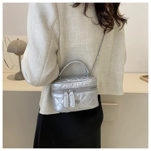 Detailed view of silver quilted crossbody bag with metal chain strap and floral accent