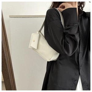 Detail of off-white minimalist underarm bag featuring a front pocket with gold round buckle