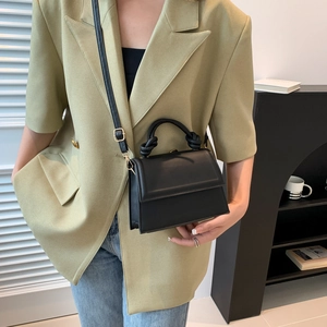 Petit sac carré noir minimaliste avec poignée nouée et détails métalliques dorés
