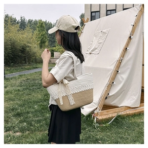 Detail of woven straw tote bag with lace bow accessory in an outdoor camping setting