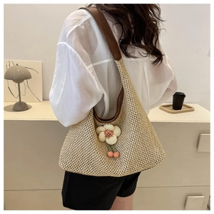 Gros plan du sac hobo en paille tressée avec décoration florale et détails en cuir marron