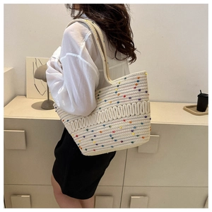 Détail d'un sac cabas en maille évidée avec des pois colorés porté à l'épaule