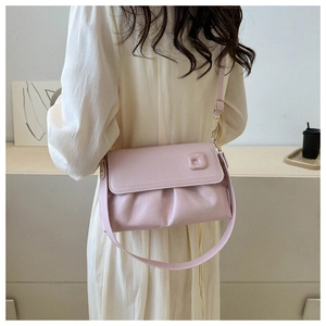 Détail d'un sac bandoulière froncé rose clair avec robe en mousseline crème pour l'été