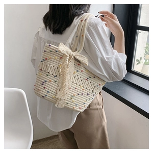Detail of cream woven tote bag featuring colorful dots and a large lace bow accent