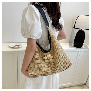 Détail du sac cabas en paille beige avec fleurs 3D et breloque rose sur bandoulière