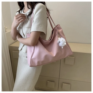 Close-up of pink large capacity faux leather tote bag with white plush ball charm detail