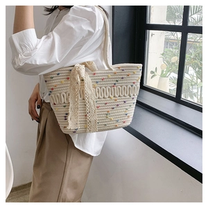 Detail of a beige woven tote bag with colorful polka dots and a delicate lace bow accent