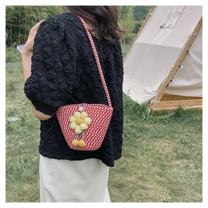 Detail of red and white plaid knit bucket bag featuring a yellow 3D floral accent