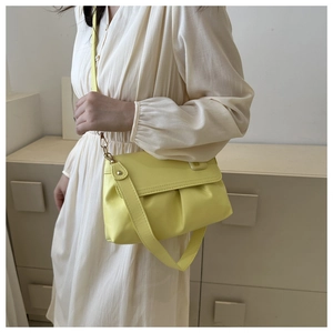 Détail du sac à bandoulière jaune clair plissé avec texture cuir et boucle dorée