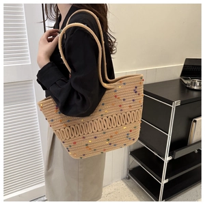 Détail du sac cabas en paille beige avec pompons colorés et bandoulière épaule