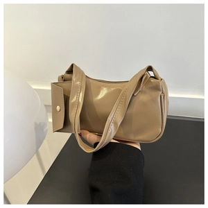 Detailed shot of beige shoulder bag with gold button side pocket and leather texture