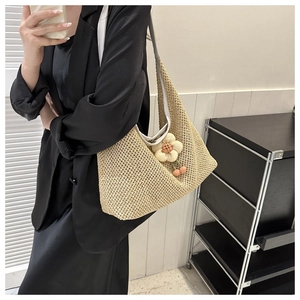 Détail du sac hobo en maille beige clair avec un pendentif floral 3D décoratif