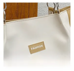Gros plan du cabas crème en similicuir avec écusson 'FASHION' marron et boucle métal