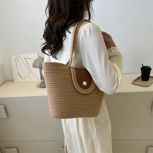 Khaki woven tote bag with dark brown leather flap and pearl button shown in home setting