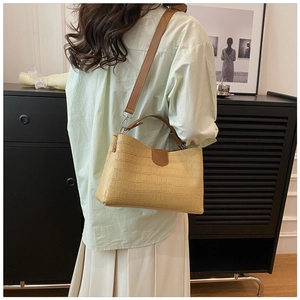 Detail of beige crocodile pattern tote bag with brown leather straps and silver metal hooks