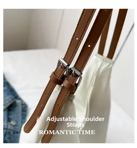 Detail view of the white nylon tote bag showing adjustable brown leather strap with silver buckle