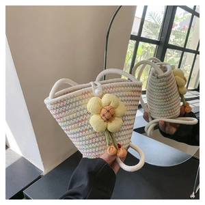 Detail of hand-woven bucket bag featuring floral charms and pearl button closure