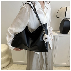 Large black matte leather tote bag shown on model with creative sunglasses charm