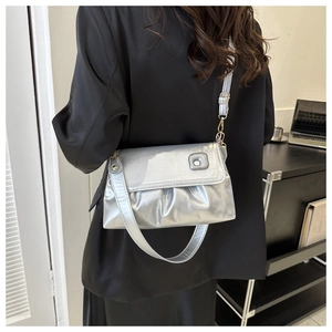 Sac à bandoulière argenté plissé avec détails dorés porté par un modèle