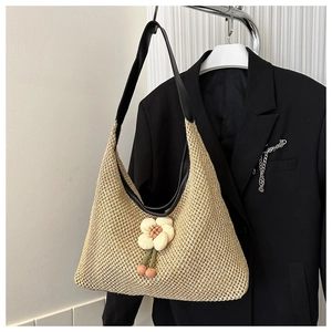 Détail du sac cabas en paille avec pendentif fleur 3D et bandoulière en cuir noir