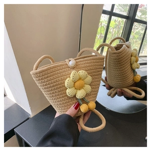 Detail of straw woven bucket bag featuring sunflower decor and pearl button closure