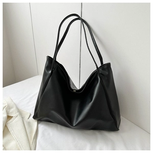 Close-up detail of soft black PU leather tote bag with fine texture and magnetic buckle
