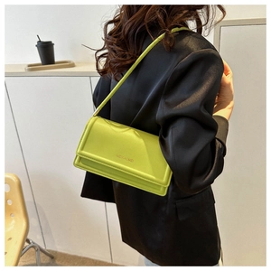 Model wearing fluorescent green leather underarm bag against a black blazer contrast