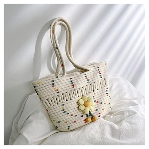 Detail of hand-woven beige shoulder bag with colorful dots and a 3D yellow daisy decor