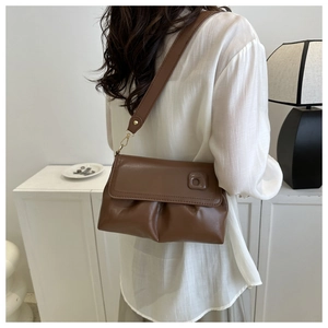 Détail du sac à bandoulière en cuir plissé caramel avec crochets dorés et large sangle
