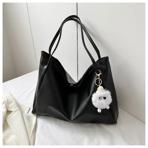 Detail of black soft PU leather tote bag with wavy rim and cute sheep plush charm