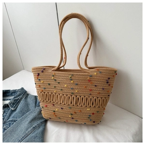 Gros plan du sac cabas tissé kaki avec pompons en peluche colorés et bretelles d'épaule