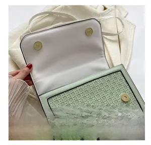 Close-up of mint green woven crossbody bag featuring dual gold magnetic snap closures