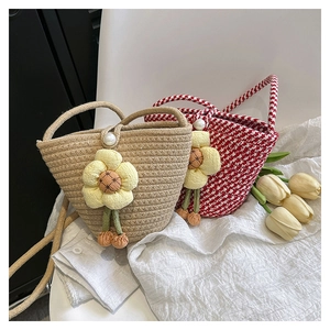 Detail of woven bucket bags with floral charms and pearl closure for summer style