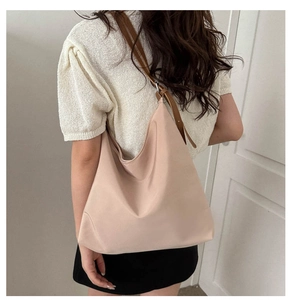 Side view of a large apricot Oxford tote bag with brown leather strap on a model