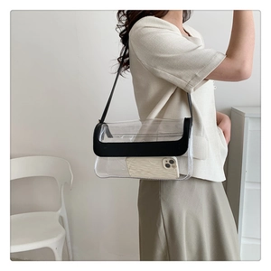 Détail d'un sac à épaule en PVC transparent avec bordure en cuir noir porté par un modèle