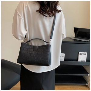 Detail of black crocodile pattern tote bag shown in professional office setting