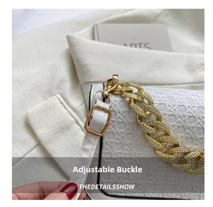 Detail of adjustable white leather strap with golden metal buckle and chain handle