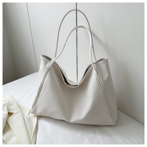 Detail of a minimalist white leather tote bag featuring a golden magnetic closure and thin straps