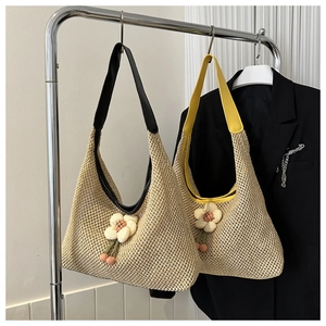 Vue détaillée du sac cabas en paille tissée avec breloques fleurs et larges anses en cuir