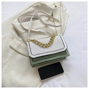 Detail of color-block woven crossbody bag featuring gold chain and textured flap