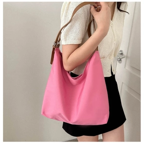 Detail of pink large capacity tote bag with brown leather shoulder strap and metal buckle