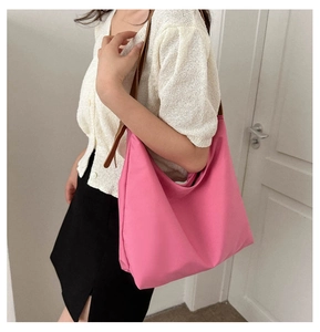 Bright rose pink nylon tote bag with brown leather straps shown on shoulder
