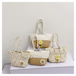 Detail of four handmade straw tote bags with floral daisy patterns and colorful accents