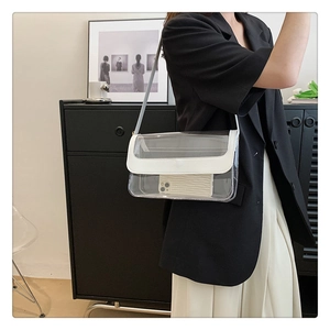 Détail d'un sac bandoulière en PVC transparent avec bordure en similicuir blanc sur blazer