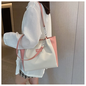 Détail de la bandoulière en chaîne et cuir et plaque logo sur le sac cabas rose
