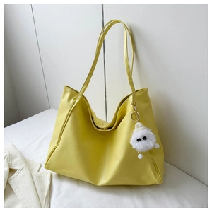 Detail of soft yellow tote bag featuring a cute white plush doll pendant and smooth texture